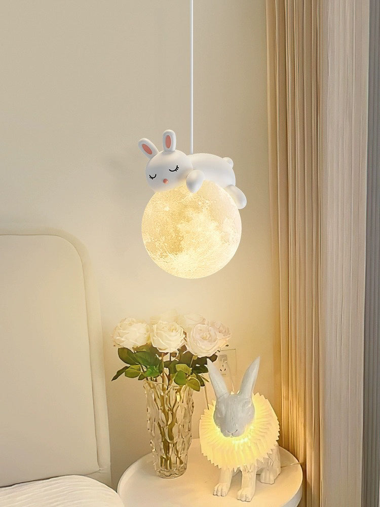 Decorative lamp with rabbit design on a nightstand next to a vase with flowers.