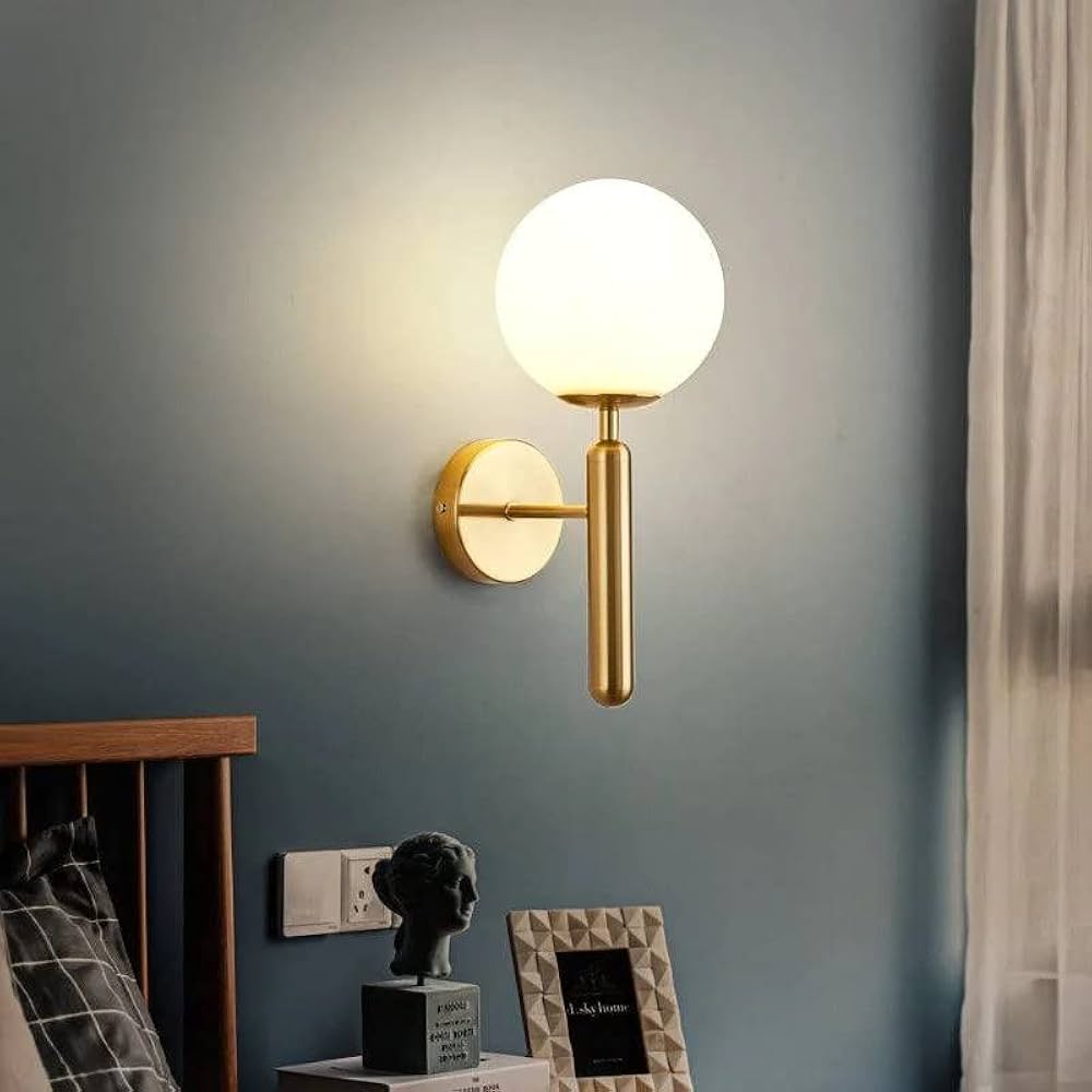 Wall-mounted lamp with a gold fixture and white globe on a gray wall.