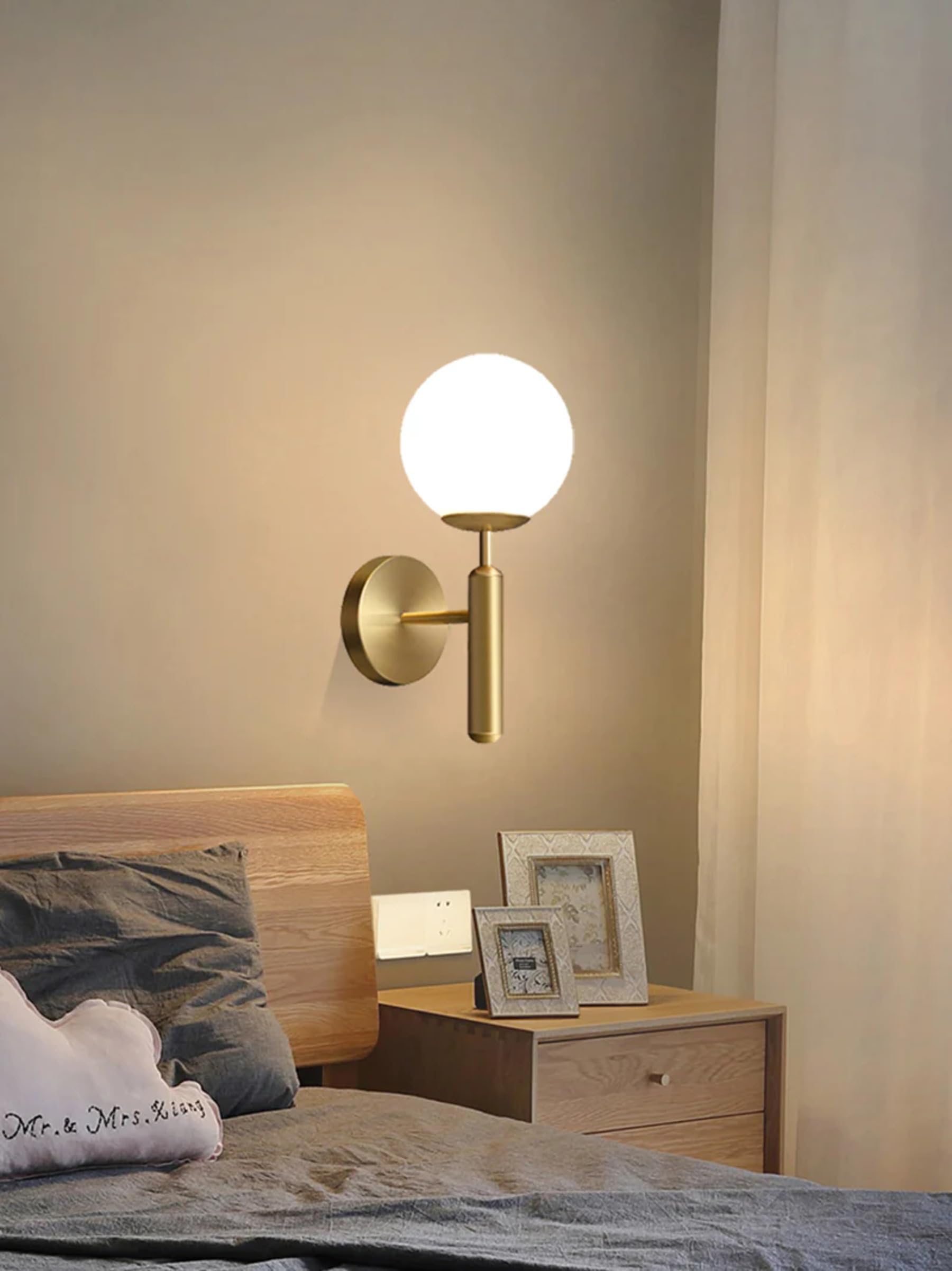 Wall-mounted lamp in a bedroom setting with a bed and nightstand.