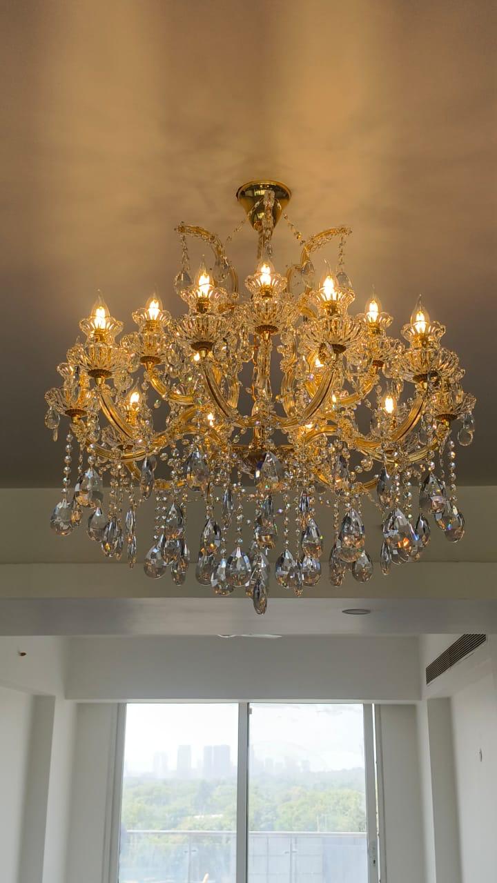 Gold chandelier with crystal accents hanging in a room with large windows.