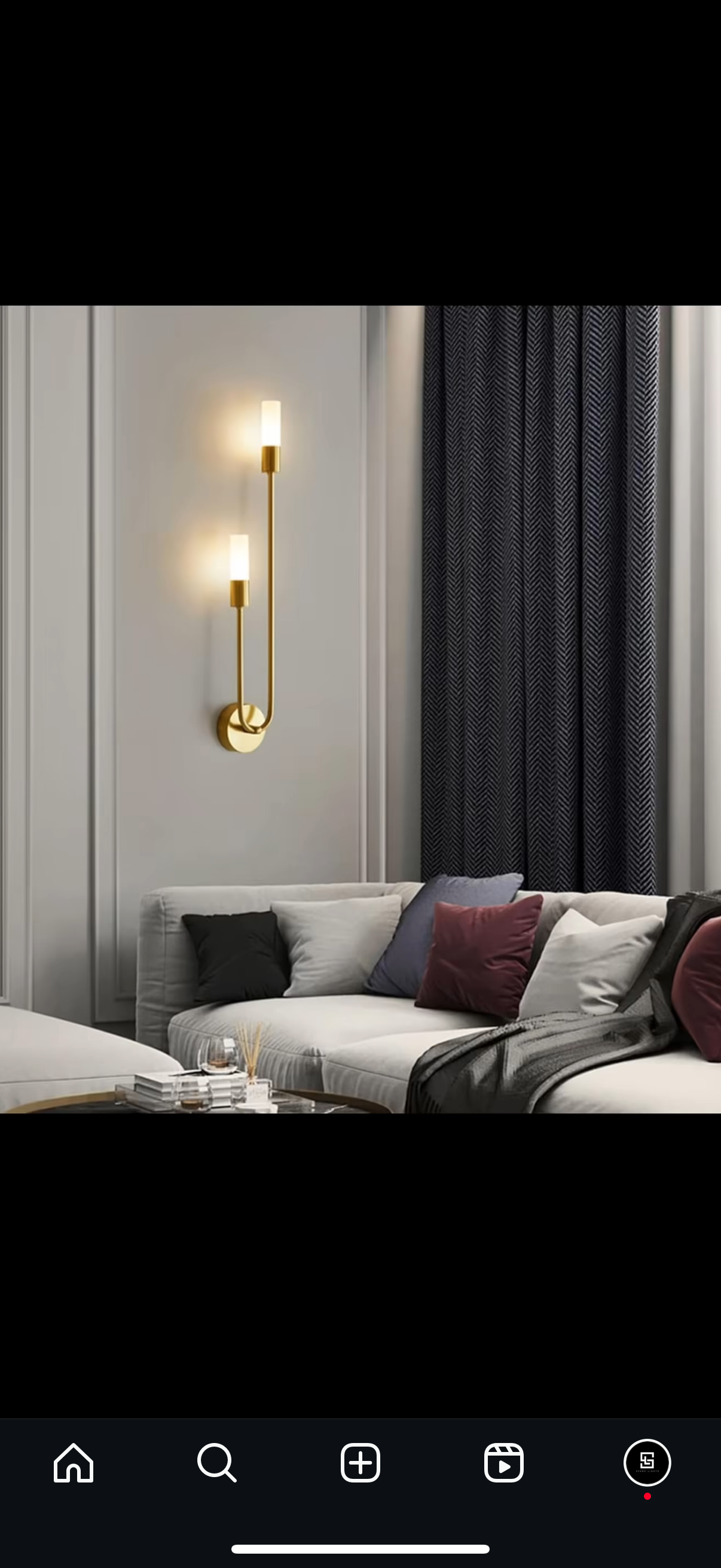 Modern living room with a gray sofa, decorative pillows, and wall-mounted gold sconces.