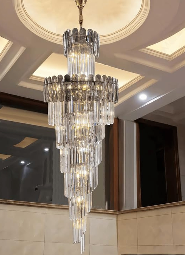 A spiral crystal chandelier with golden accents, hanging from the ceiling, reflecting light through its crystal tiers.
