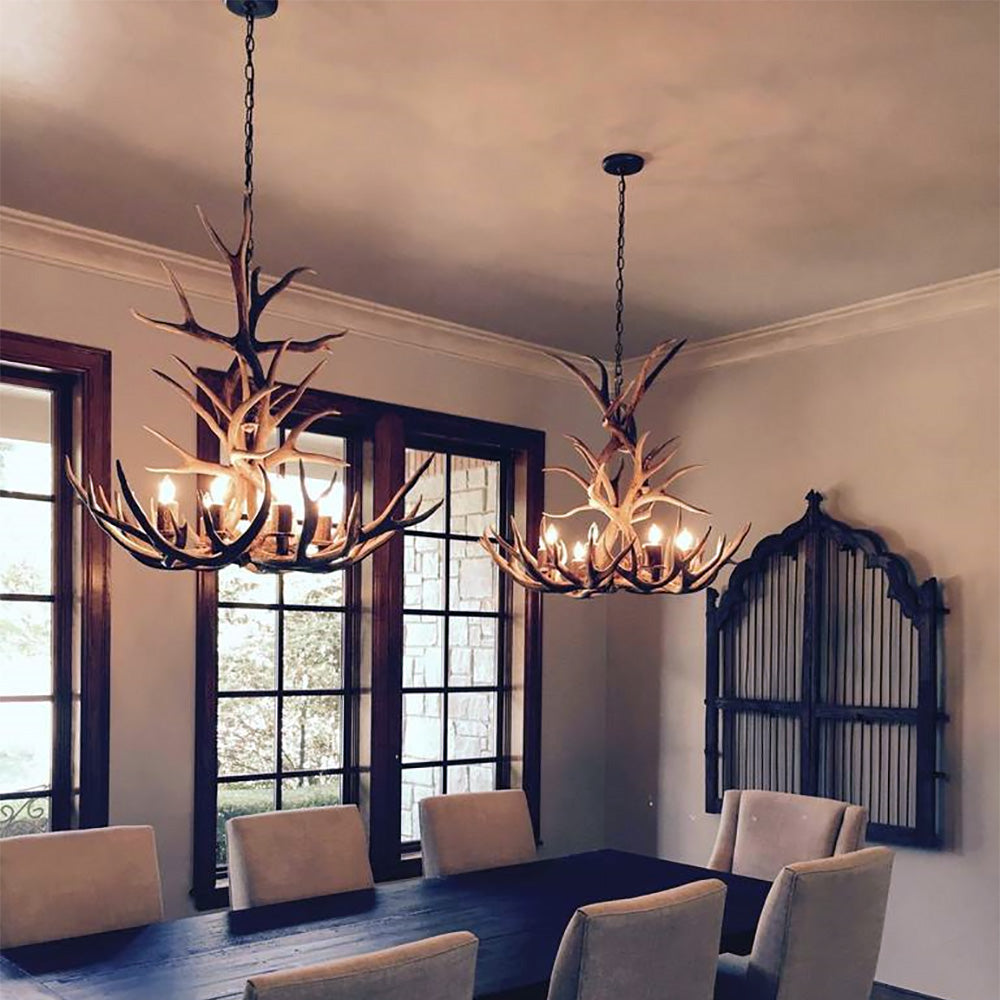 Dining room with antler chandeliers hanging above a table and chairs.