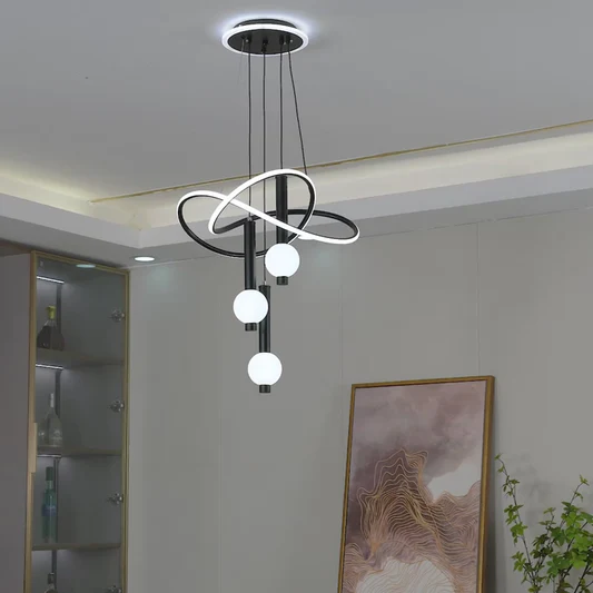Modern pendant light fixture hanging from the ceiling in a room with a painting and plant.