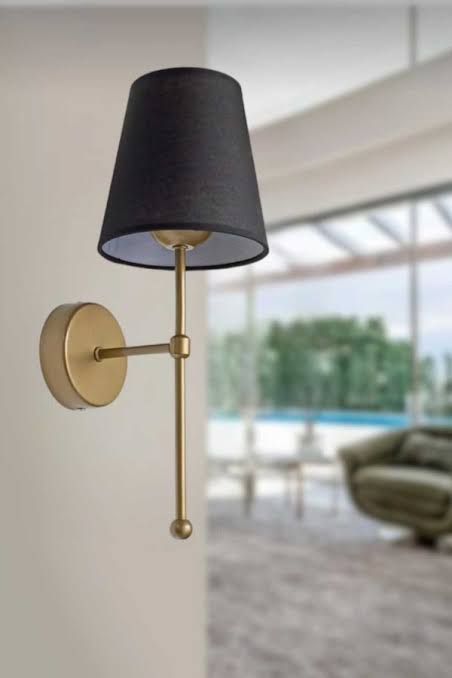 Wall-mounted lamp with black shade and gold fixture in a home setting