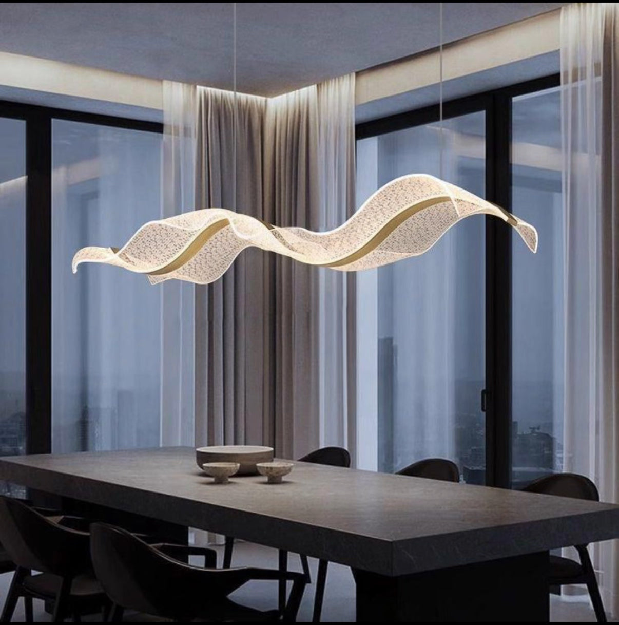 Modern pendant light hanging above a dining table with large windows in the background