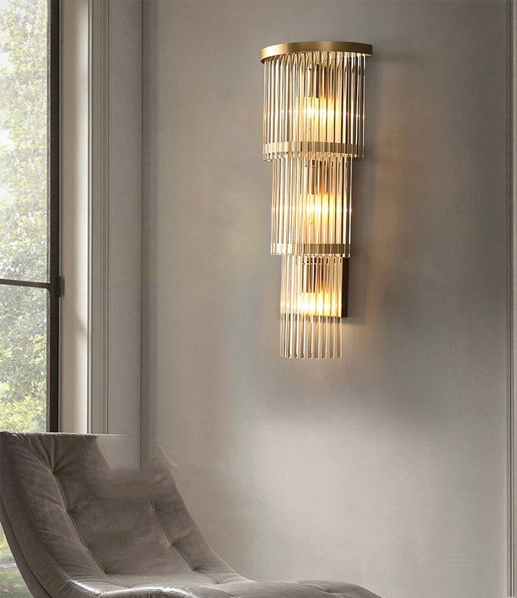 Modern wall sconce with glass accents on a neutral wall next to a window.