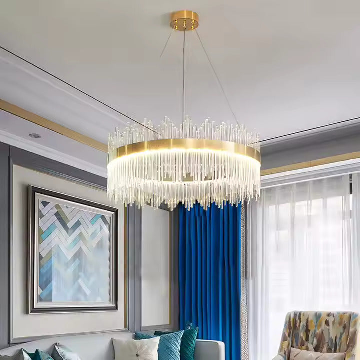 Gold chandelier hanging in a living room with blue curtains and artwork.